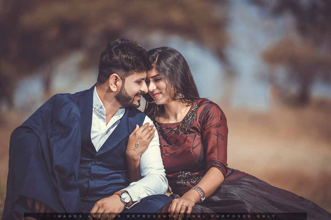 Romantic pre-wedding photo of a couple sitting close and smiling, lost in each other’s eyes.