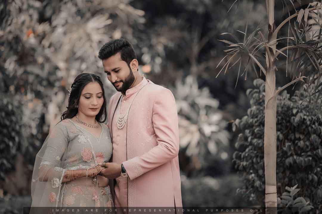 Indian couple in pastel traditional outfits sharing an intimate moment during a pre-wedding photoshoot in a lush garden.
